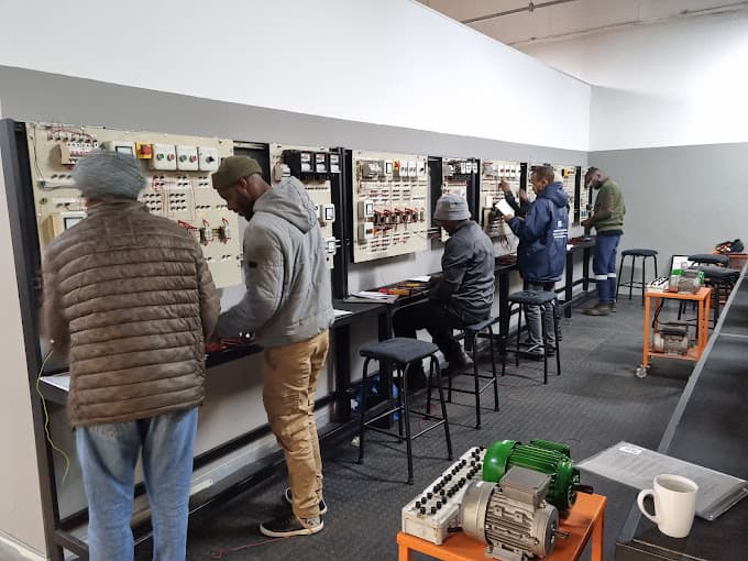 Learners wiring circuits on a row of electrical training panels